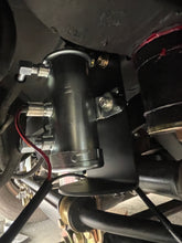 Load image into Gallery viewer, A close-up of a black cylindrical mechanical component with metal fittings, a red wire, and mounting hardware, photographed in a tight technical setting.
